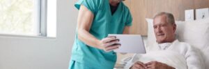 A doctor shows a patient who is laying in bed a chart