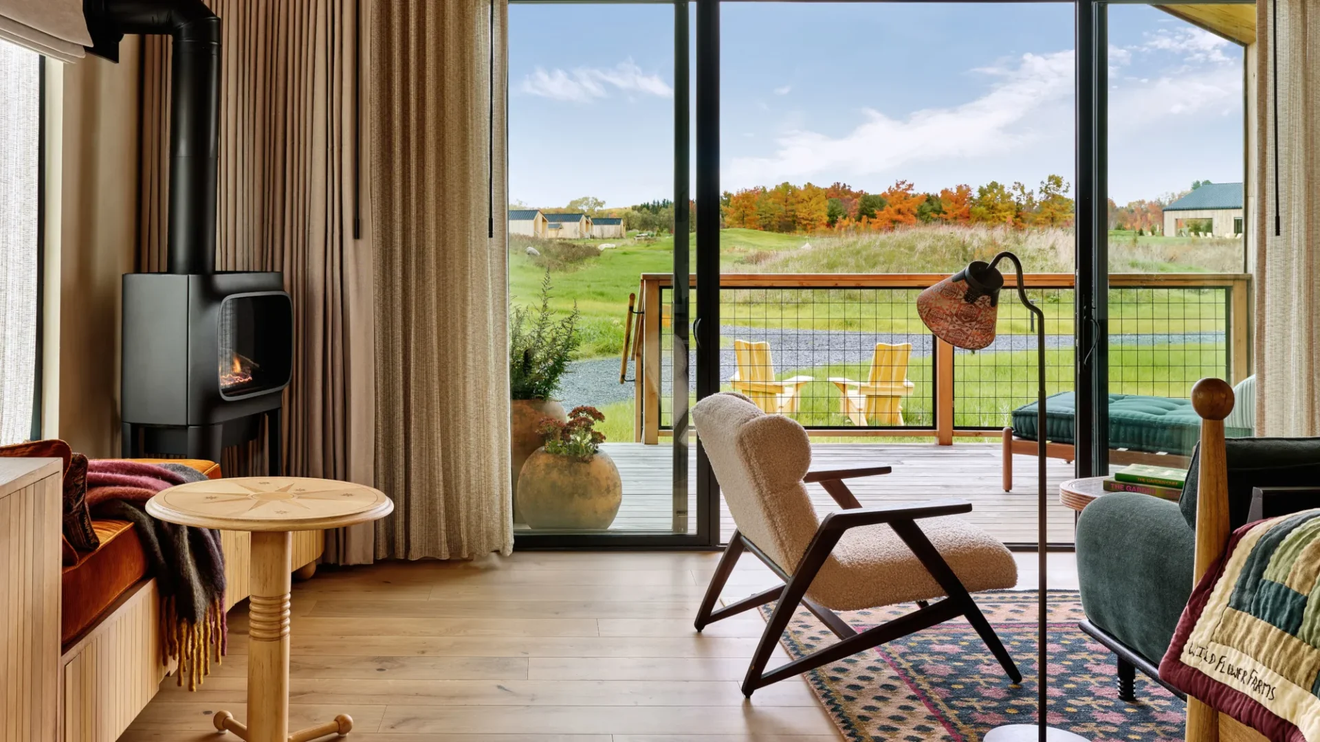 A view from a cottage at the Wildflower Resort, showing furniture, a fireplace, and a floor-to-ceiling window showing off the view