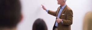 A group of college students listen to a lecture given by a professor