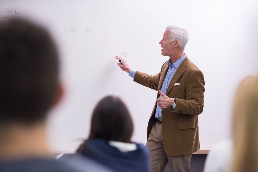 A group of college students listen to a lecture given by a professor