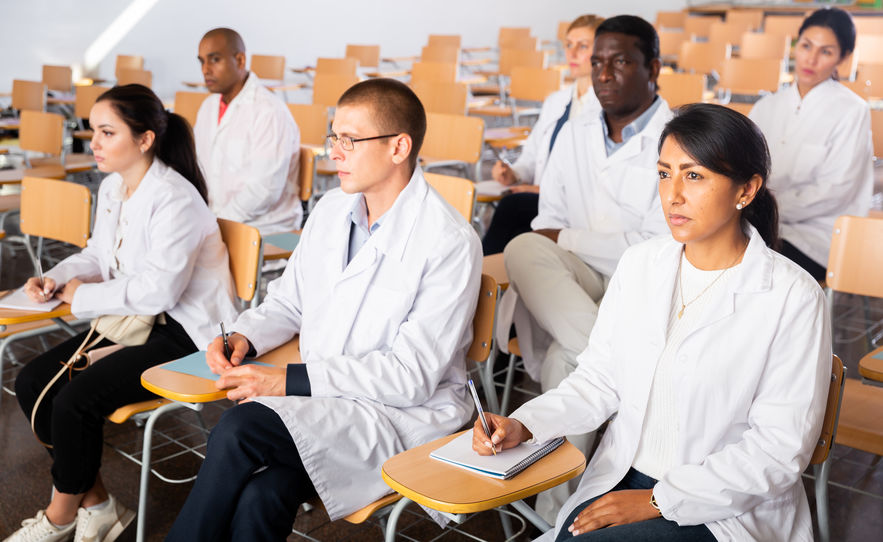Multiethnic group of young adult medicals attentively listening to lecture during training program for health workers