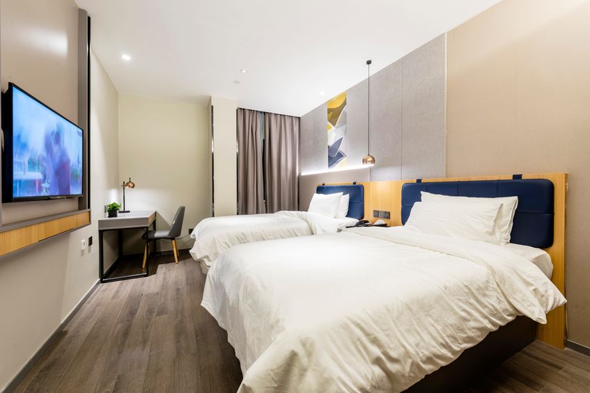 Round mirror and clock above bed with pillows in bright bedroom interior with flowers. real photo